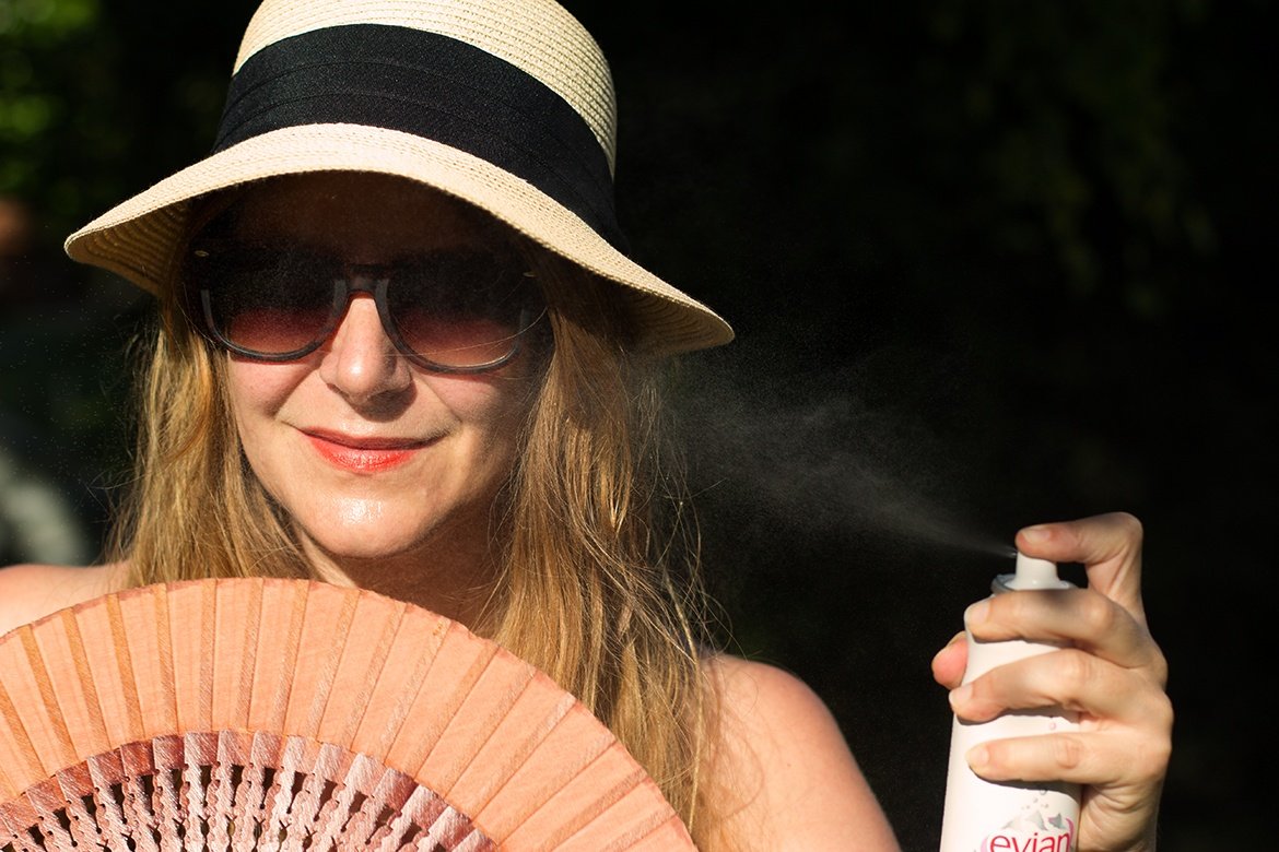 Femme sous le soleil avec un chapeau, un éventail et un brumisateur